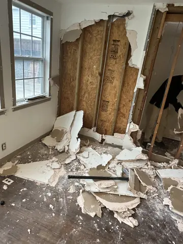 Opened interior wall beneath a window during demolition.