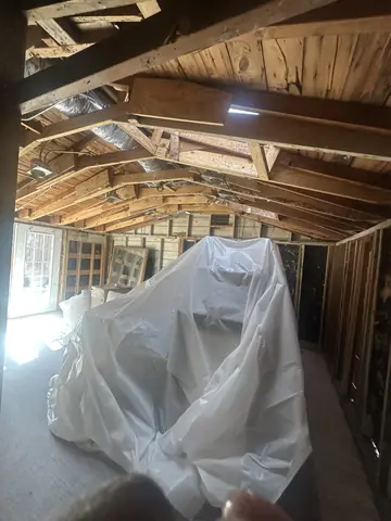 Roof and wall framing exposed above protected furnishings.