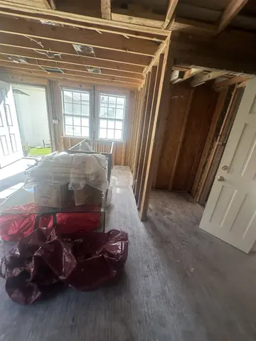 Opened walls and exposed framing around a residential window.