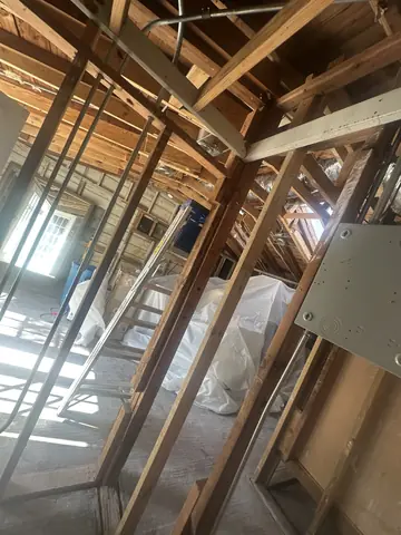 Roof framing visible above temporary protection during interior demolition.