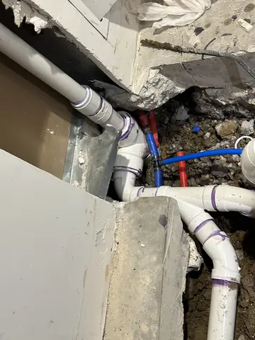 Exposed plumbing beneath the floor during commercial interior work.