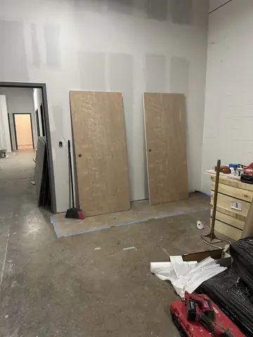 Sheet material and tools staged in a commercial room under construction.