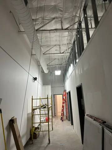 Long view down the commercial corridor before ceiling completion.