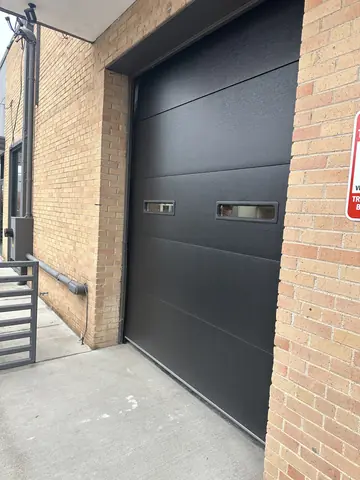 Commercial entrance with brickwork and a dark overhead door.