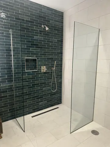 Finished green-tile shower with a glass partition.