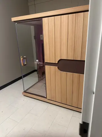 Wood-clad enclosure with a glass door in the finished fitness interior.