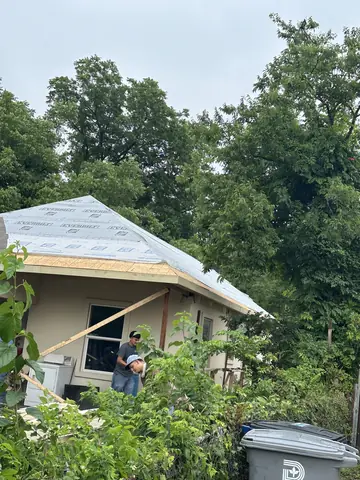 Roofing work progressing above the addition.