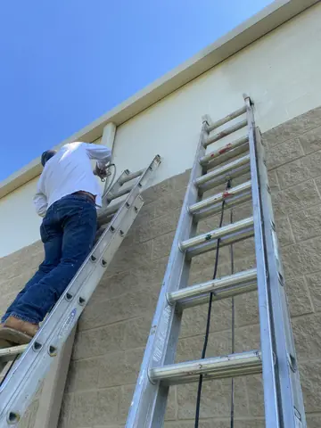Exterior painting from an extension ladder at a commercial property.