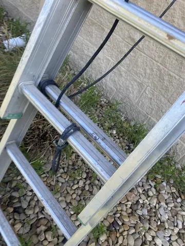 Ladder and paint hose beside the commercial exterior wall.