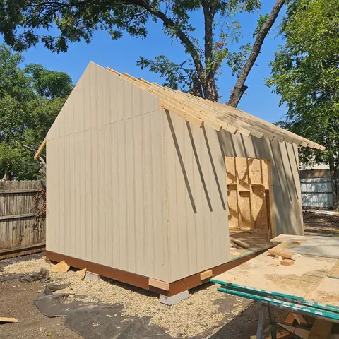 Storage building with siding installed and the roof still open.