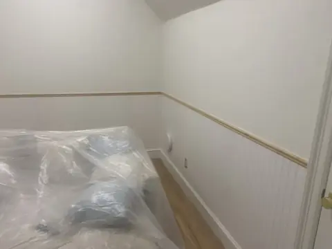 Protected furniture beside newly installed wall paneling and trim.