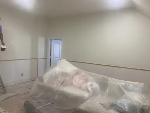 Room-wide view of wall paneling with furnishings covered during work.