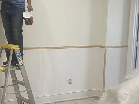 Ceiling work above the new wainscoting; furnishings remain protected.