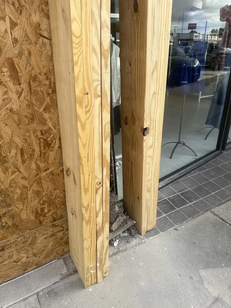 New solid-wood support posts installed at a commercial storefront entry to carry the load during structural repair