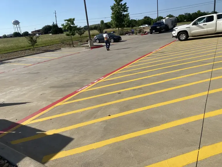 Freshly painted yellow parking-lot striping and a red fire-lane curb on a commercial property