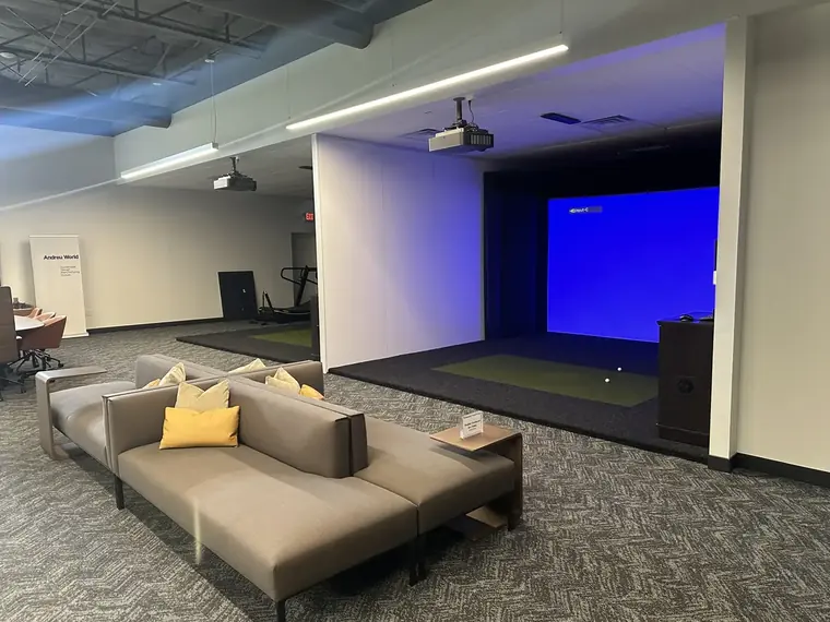 Finished commercial fitness lounge with a large LED screen, sectional seating, and recessed lighting